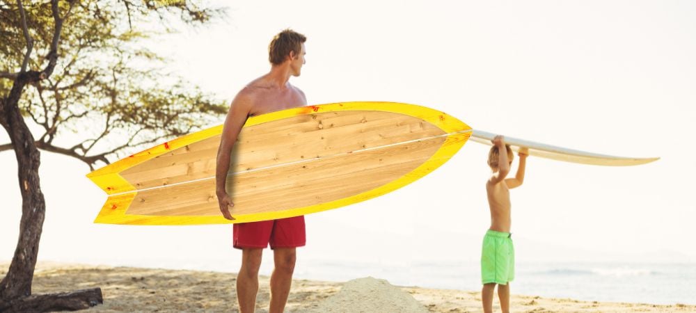 Father carrying a hard paddle board at the beach
