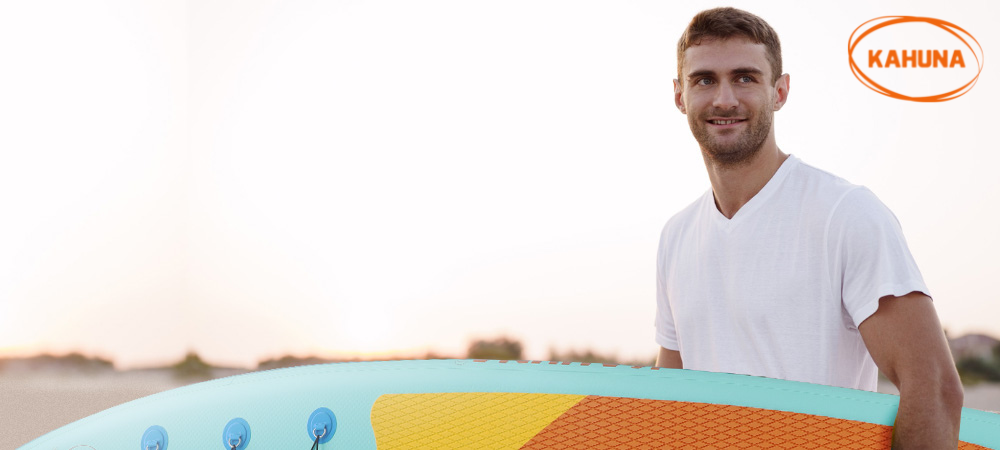 Man in white shirt carrying a paddle board