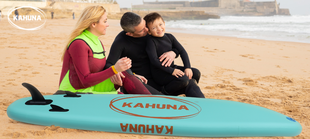 Happy family in wetsuits seated next to a paddle board