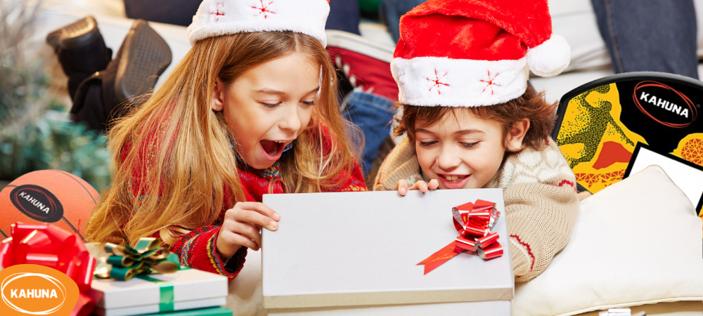 A young boy and girl opening Christmas gifts including a trampoline basketball set