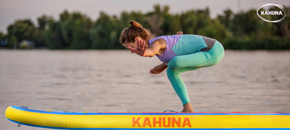 Woman bent forward doing SUP yoga on the beach