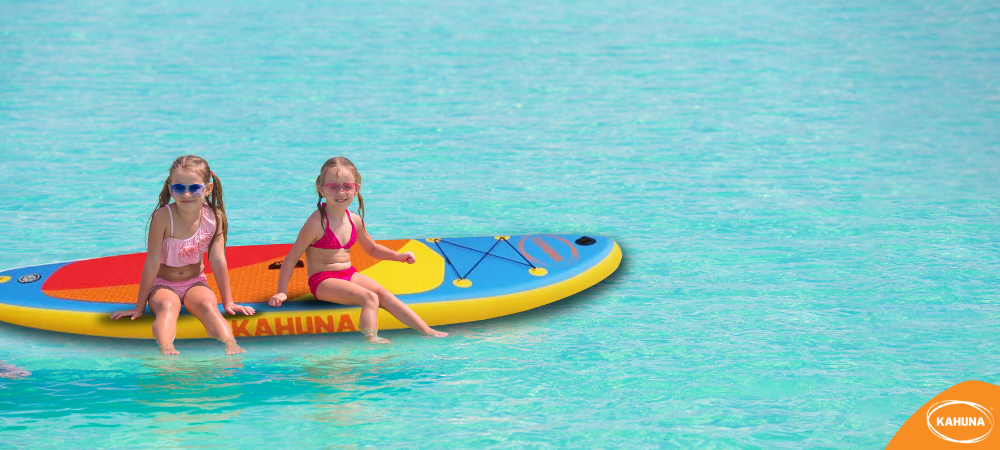 Two little girls sitting on a paddle board