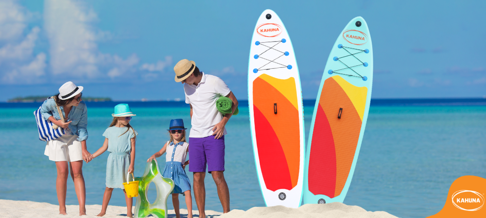 Family at the beach next to two Kahuna paddle boards