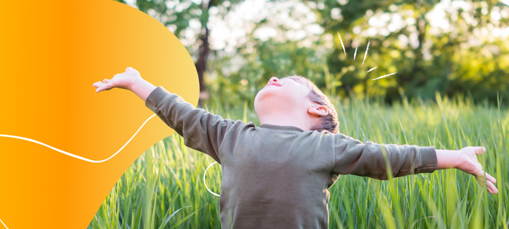 A young boy with outstretched arms enjoying the weather outdoors
