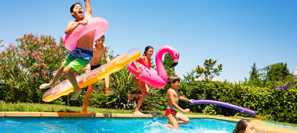 Kids jumping into a pool during a summer birthday party