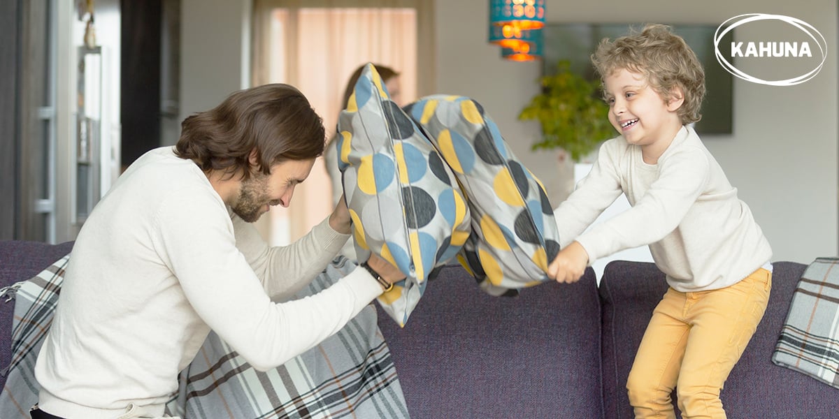 Young boy in a pillow fight with his dad