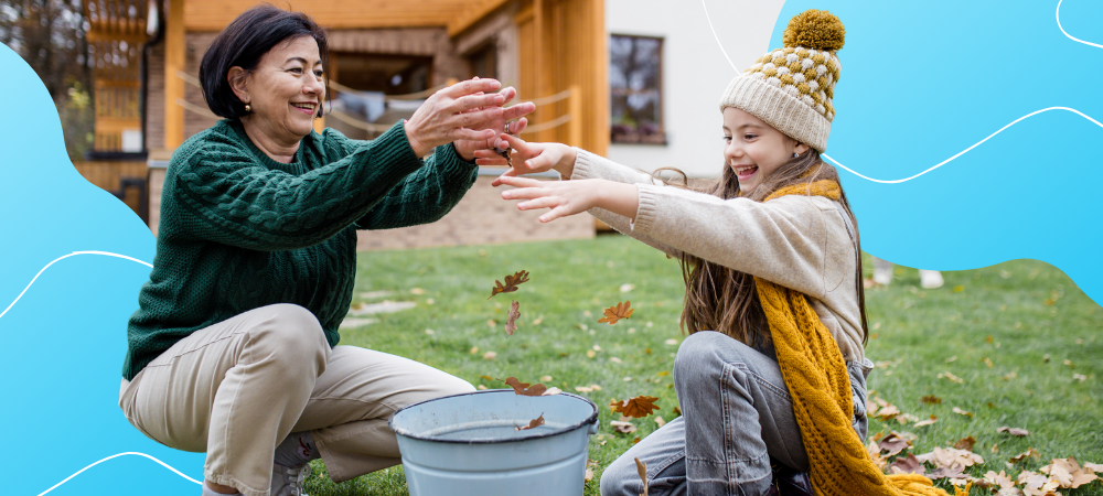 A young girl and a middle-aged woman laughing while putting leaves in a bucket