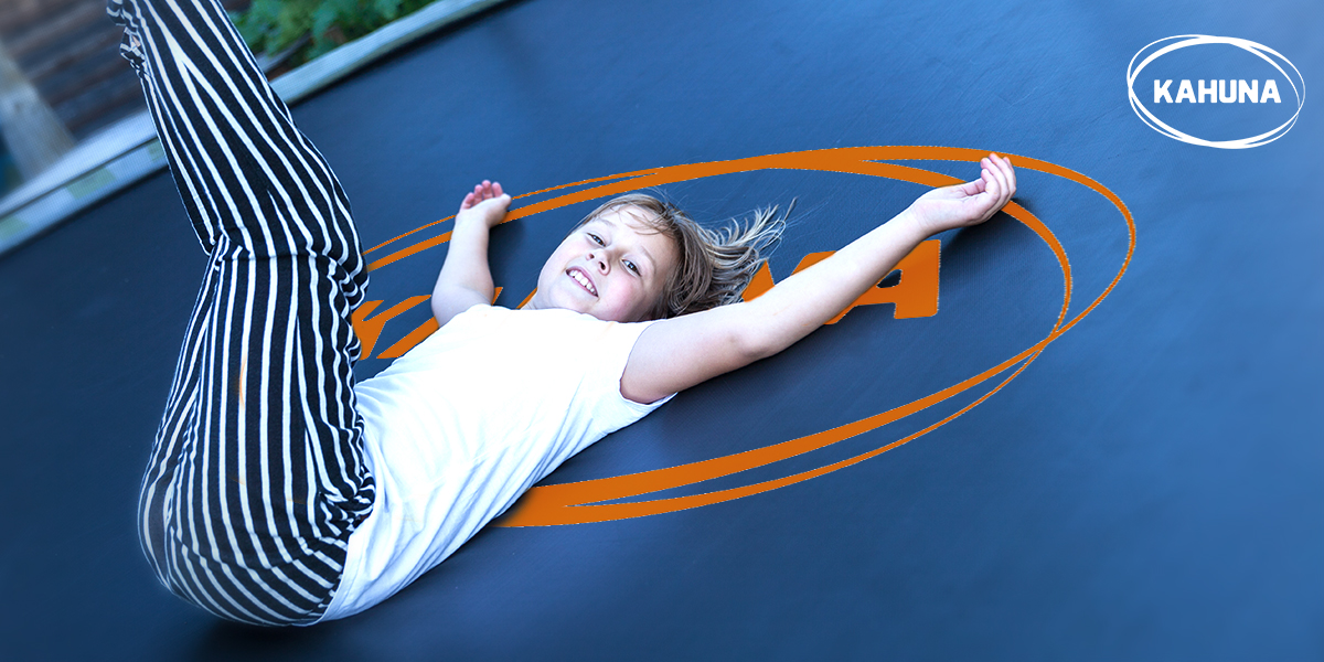 Happy child laying down alone on a trampoline