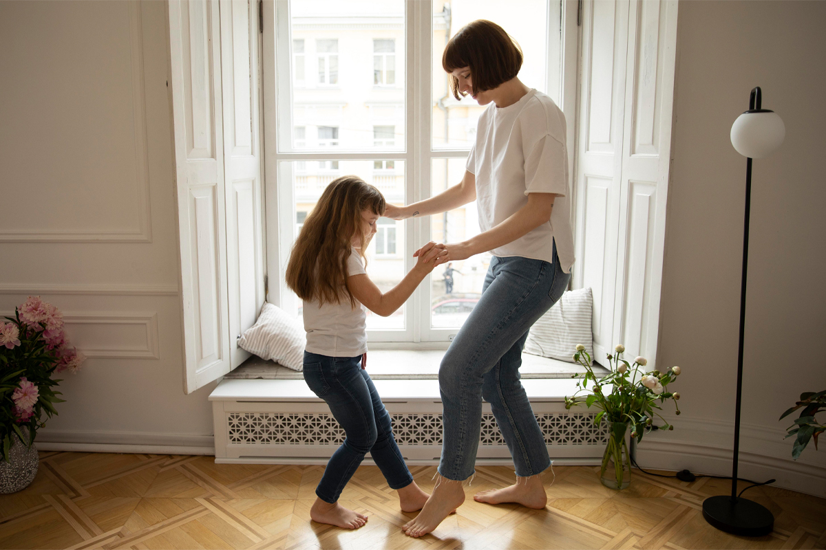 Young mom dancing in the living room with her daughter
