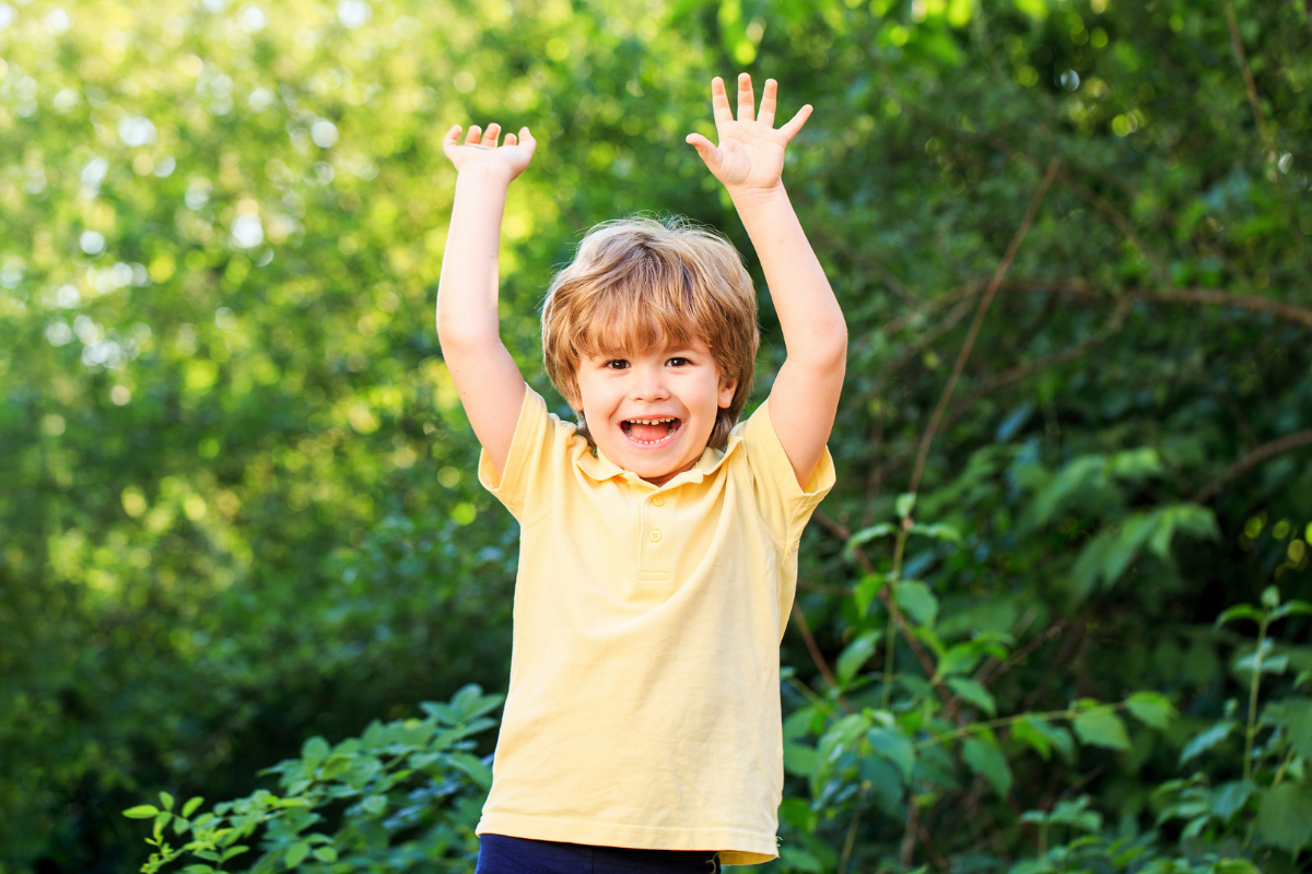 An excited young boy with his hands up in the air