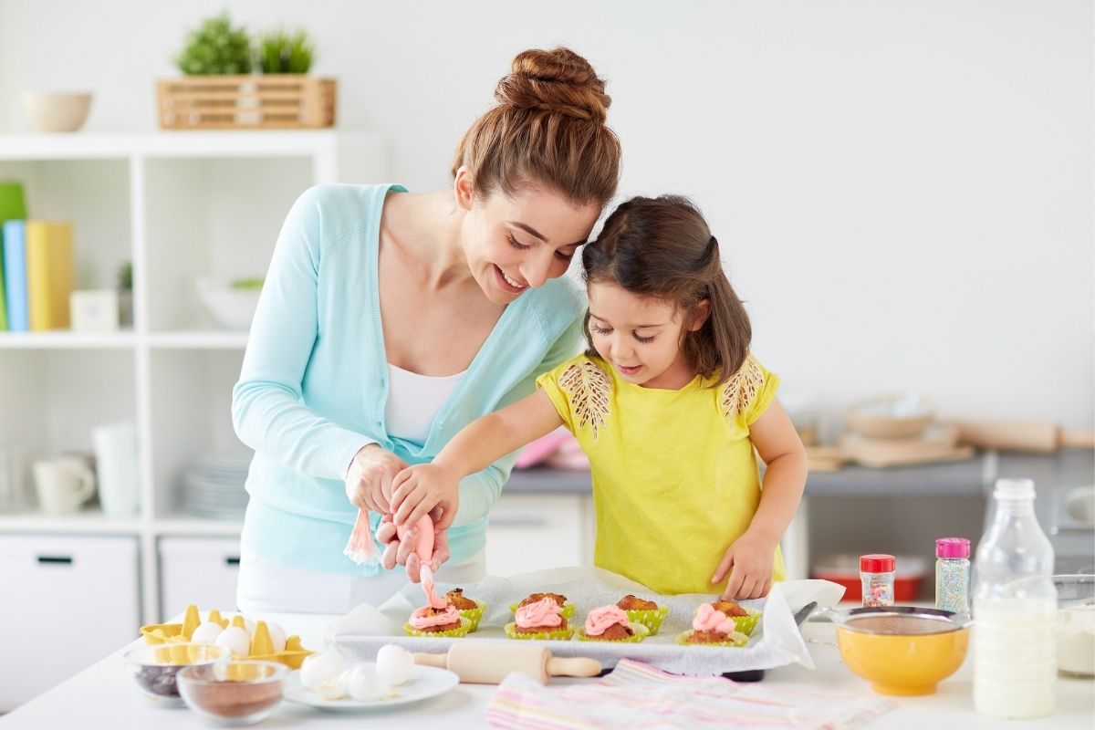 Young mom decorating cupcakes with her daughter