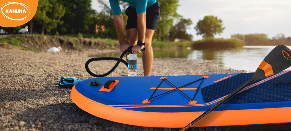 Manual SUP pump being used on a lake shore